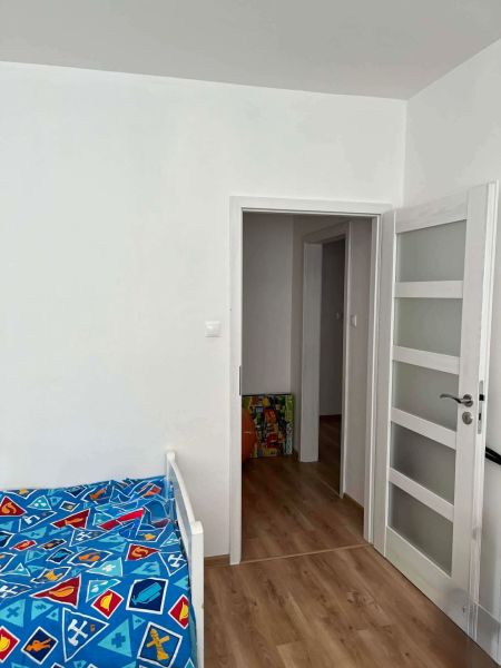 Children's room with a bed, white doors, and a floor with a wooden decor in a 3-room apartment.