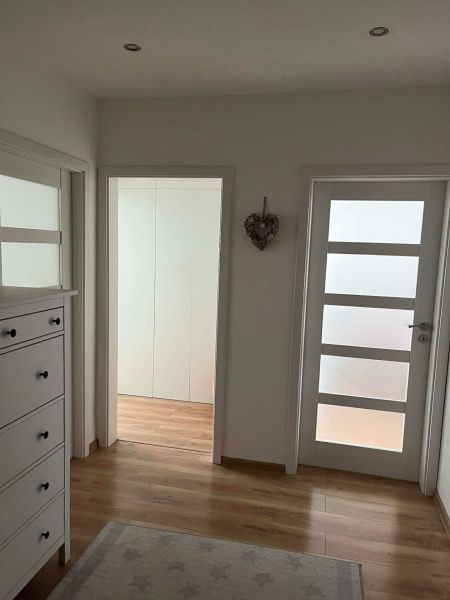 Interior of a 3-room apartment with white furniture and a floor with a wooden decor.