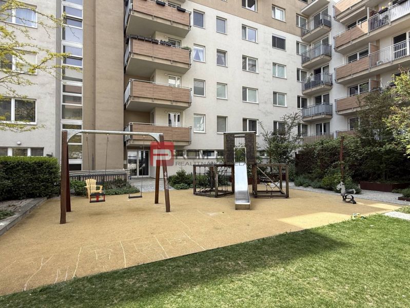 The courtyard on Galvaniho in Bratislava with a playground, slide, and swing near a 2-room apartment.