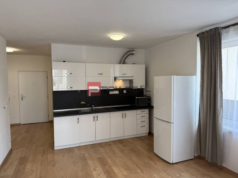 Kitchen unit with a white refrigerator and microwave oven, floor with wooden decor.