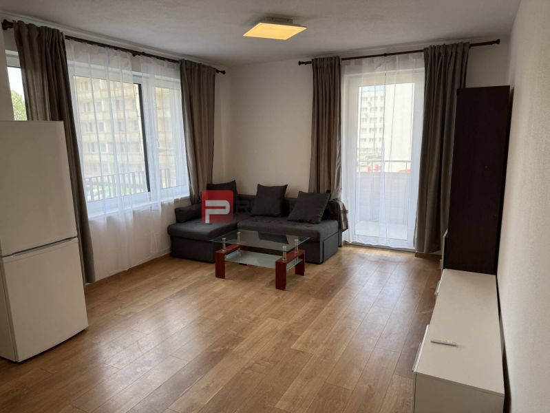 Living room of a two-room apartment with a sofa, glass table, and wood-decorated floor.
