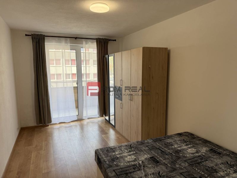A room in a 2-room apartment with a bed, wardrobe, and a wooden decor floor.
