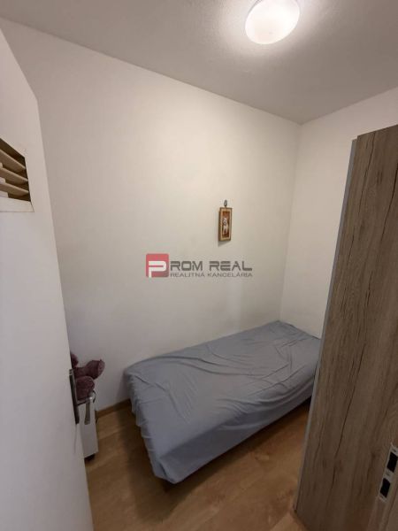 A single bed in a bedroom with wood-patterned flooring, 2-room apartment.