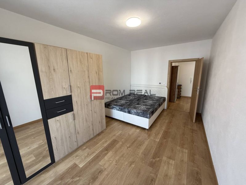 Bedroom in a two-room apartment with a wooden decor floor and a built-in wardrobe.