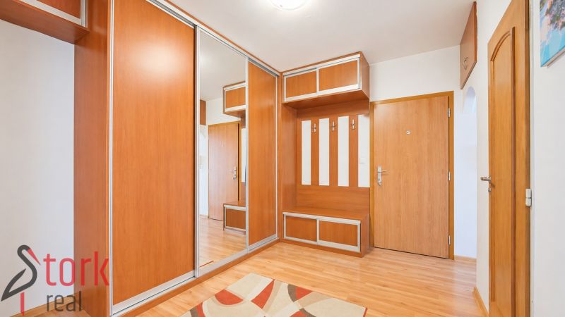The interior of the hallway in a 3-room apartment with a wooden decor floor and a built-in wardrobe.
