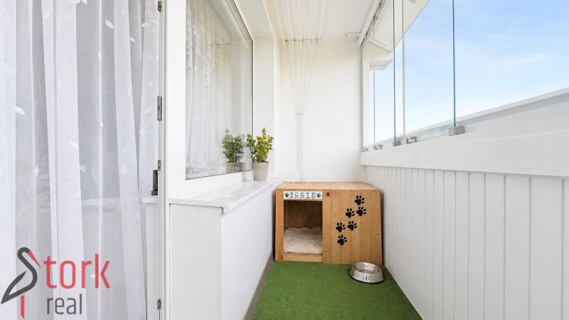 Glazed balcony with a box for a dog and a bowl in a 3-room apartment.