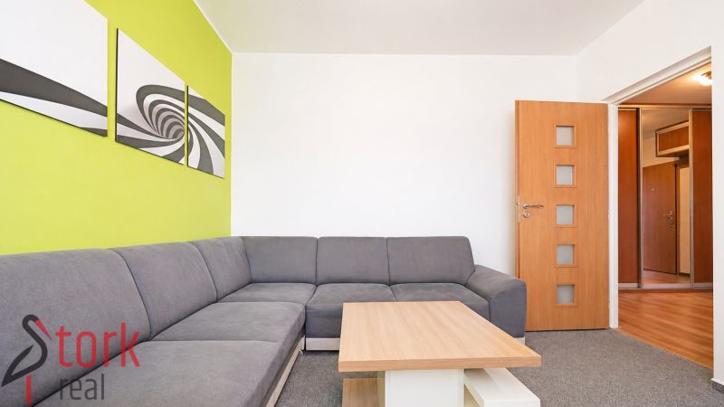 Living room with a corner sofa and a green wall in a 3-room apartment.