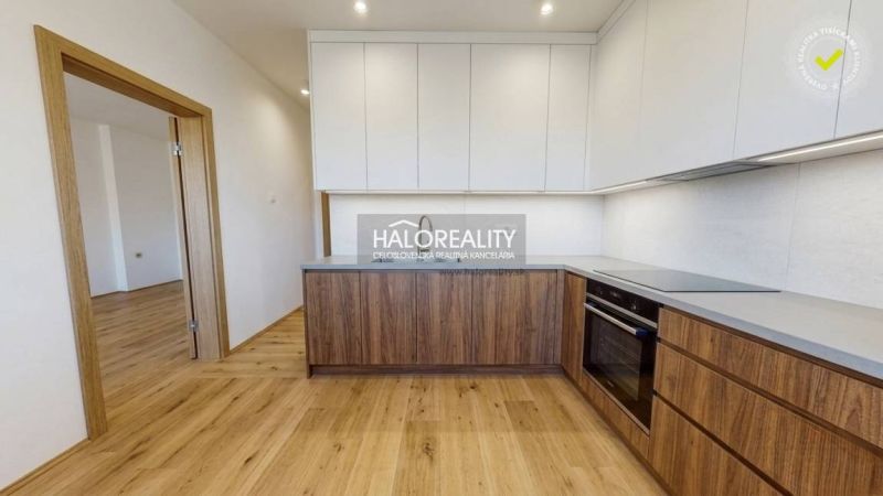 A kitchen in a 2-room apartment with a wooden decor floor and white cabinets.