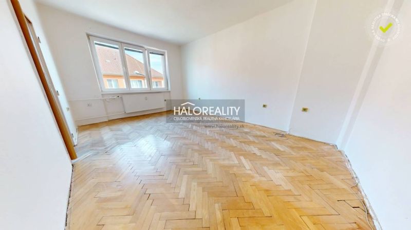 A spacious room with windows and a wooden decor floor in a 2-room apartment.