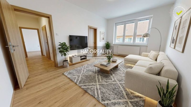 Spacious living room with a sofa, wood-patterned flooring, and large windows.
