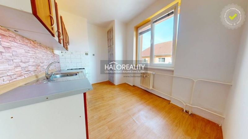 A kitchen in a 2-room apartment with a wooden decor floor and a view from the window.
