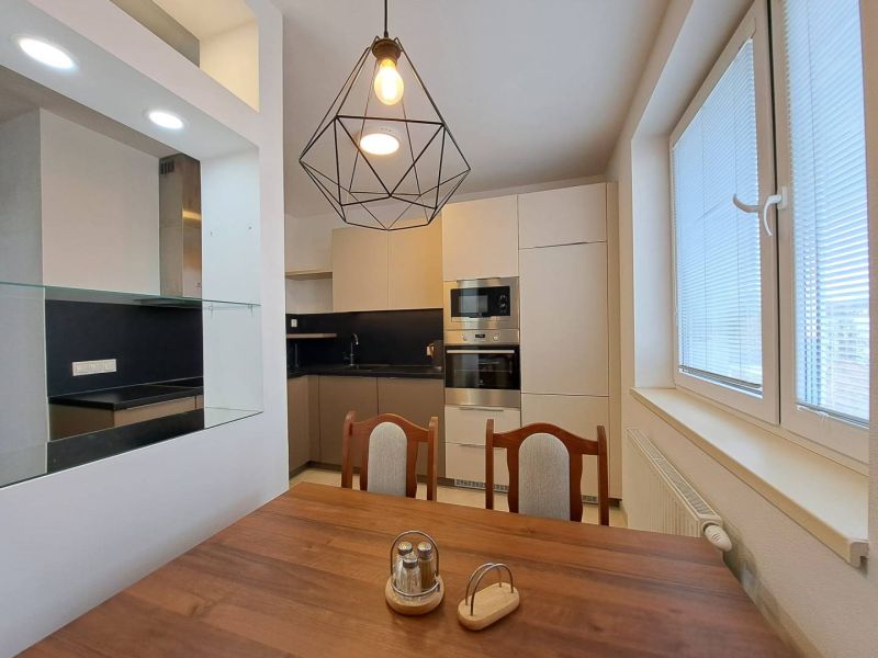 The interior of a kitchen in a 3-room apartment with light furniture and a wooden decor floor.