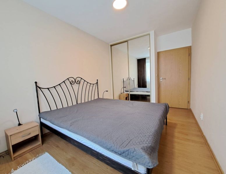 A bedroom with a metal bed, wood-decor flooring, and a built-in wardrobe in a three-room apartment.