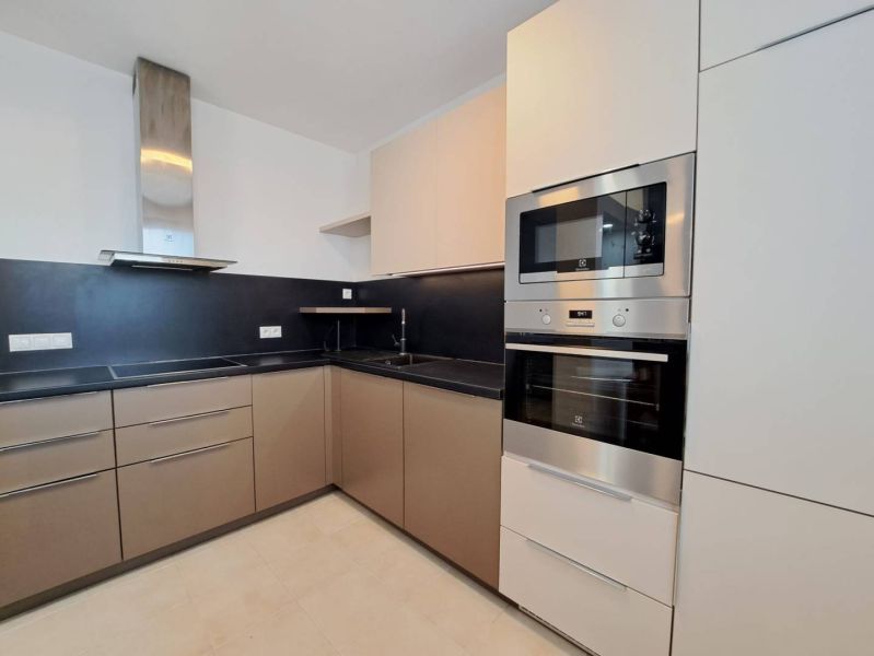 A modern kitchen in a 3-room apartment with beige cabinets and built-in appliances.