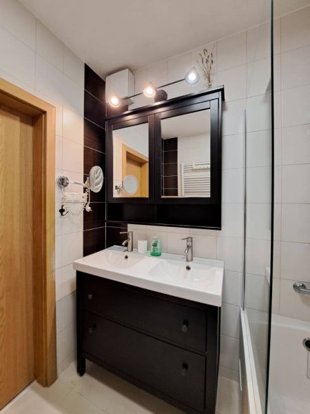 A bathroom in a 3-room apartment with a double sink and a dark mirror.