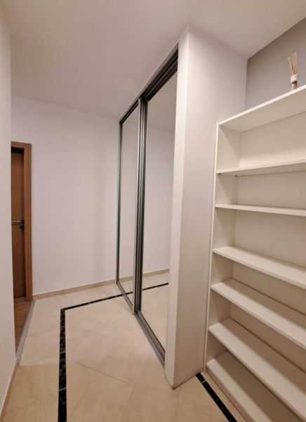 A hallway in a 3-room apartment with white walls, a built-in wardrobe, and a shelf.