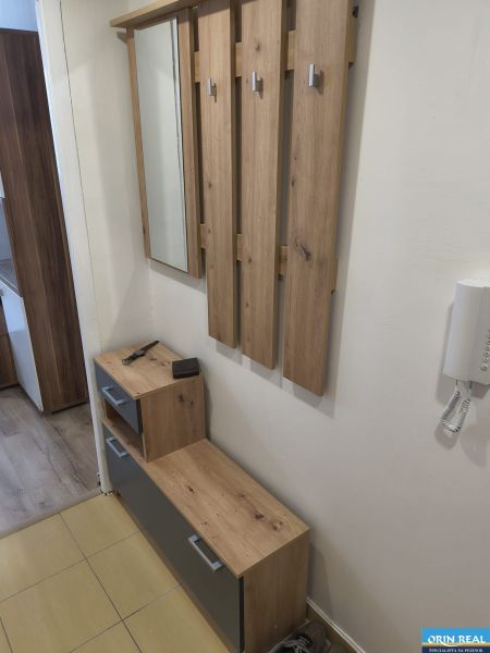 Studio apartment with a coat rack and furniture with a wood finish, view of the hallway.