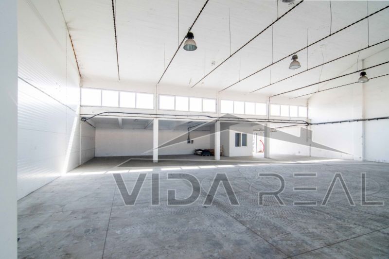 Interior of a warehouse space with a concrete floor and large windows.