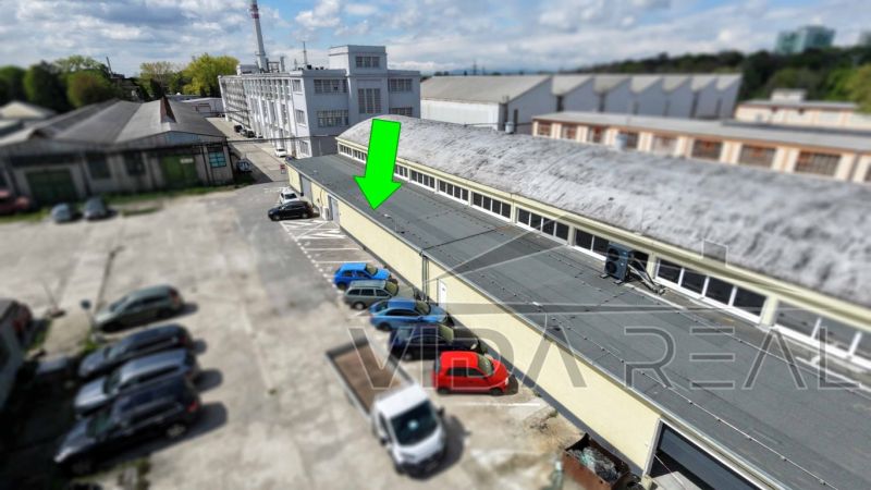 Warehouses and halls on Coburgova Street in Trnava with a parking lot and cars.