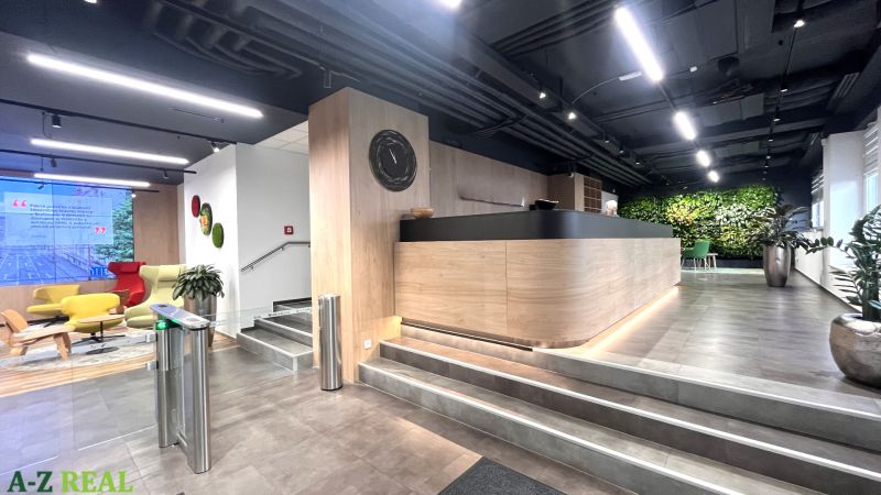 Reception in an office with wooden decor, a green wall, and modern seating.