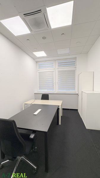 Offices with black carpet, two desks, and ceiling lighting.