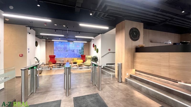 Interior of offices with modern seating, turnstiles, and flooring with wood decor.
