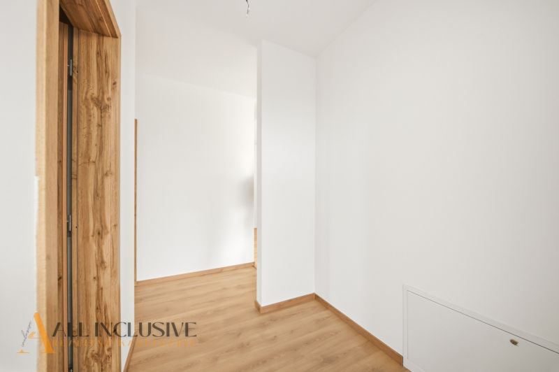A hallway in a family house with white walls and a wooden decor floor.
