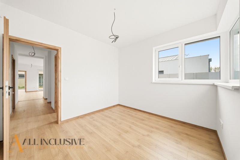 A room with a wooden decor floor in a family house, a bright room with a large window.