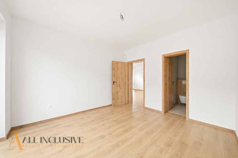 A room in a family house with a wooden decor floor and white walls.
