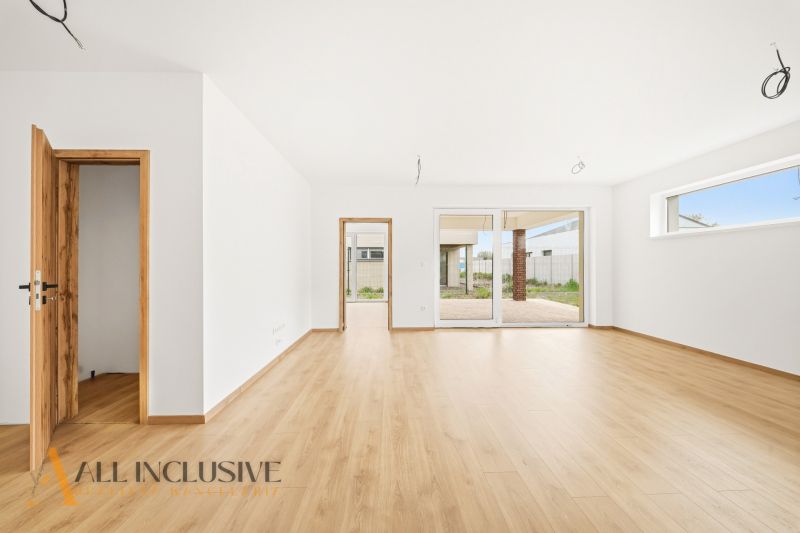 Interior of a family house with a wooden decor floor, open doors leading to the terrace.