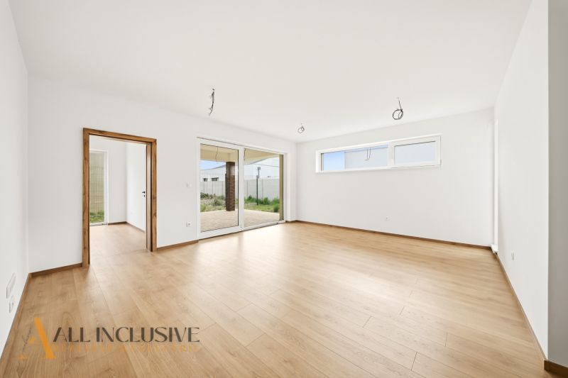 Spacious interior of a family house with a wooden decor floor and large windows.