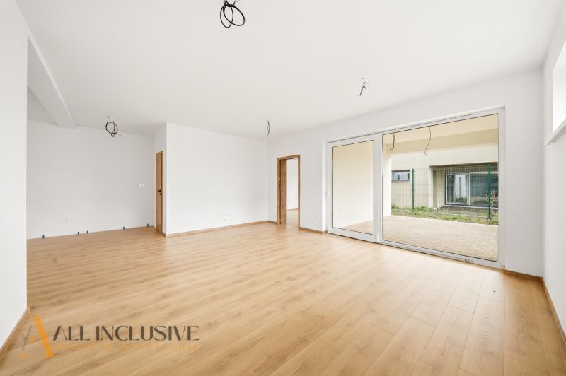 A spacious living room in a family house with a wooden decor floor and large doors to the garden.