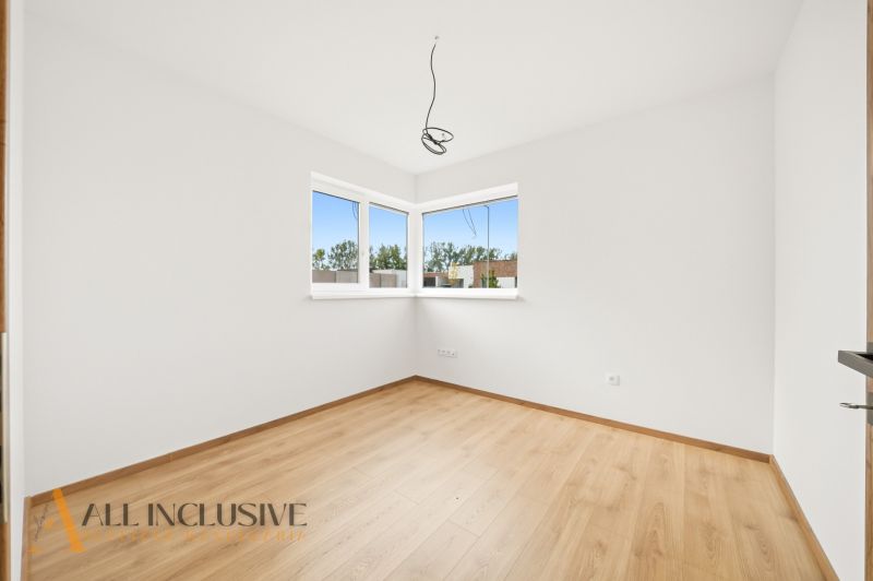 A bright room with windows and a wooden decor floor in a family house.