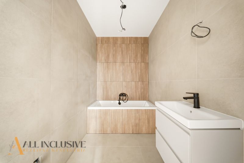 A bathroom with a bathtub and a sink in a family house with wooden decor paneling.
