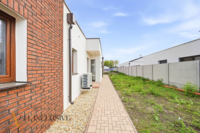Exterior view of a family house in Dunajský Klátov with brick cladding and a grassy area.