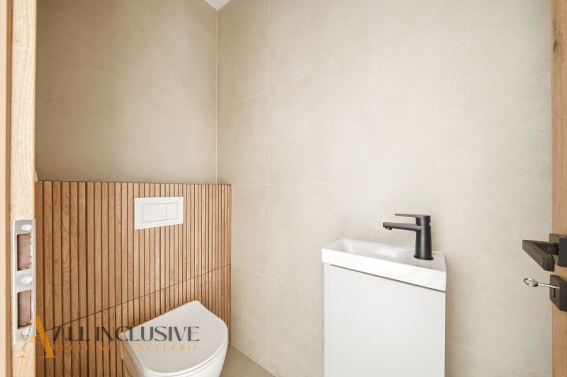 A bathroom in a family house with a wall featuring a wooden decor and a minimalist sink.