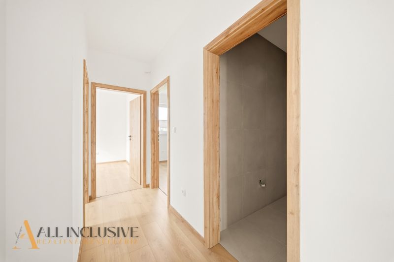 A hallway in a family house with a wooden decor floor and light-colored walls.