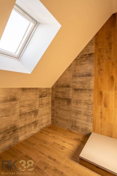 Attic bathroom with wood-patterned flooring and a skylight in a family house.
