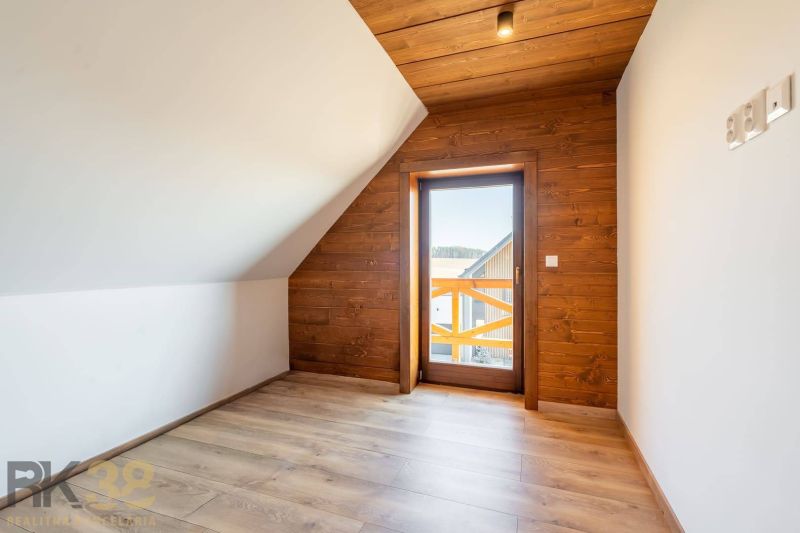 An attic room in a family house with a wooden decor floor and wooden paneling.