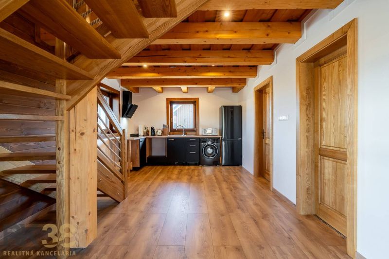 A kitchen in a family house with wooden ceilings, a floor with a wooden decor, and modern furniture.