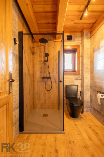 A bathroom in a family house with black sanitary equipment and a floor with a wood decor.