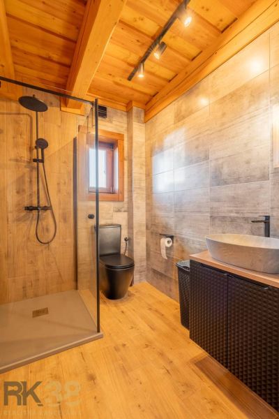 A family house bathroom with a wooden decor floor, a shower corner, and a sink.