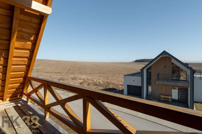 The view from the terrace of a family house in Stará Lesná to the open field and the neighboring house.