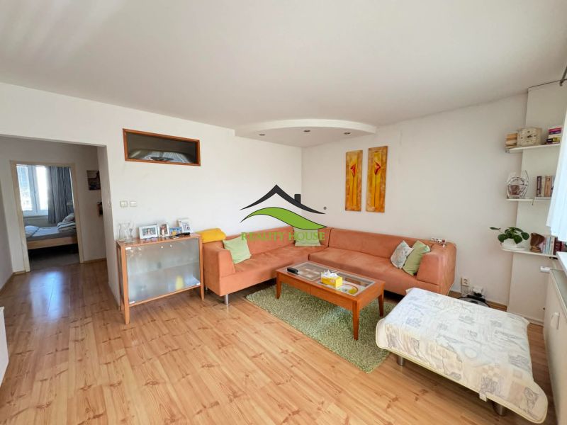 A living room in a 4-room apartment with a wooden decor floor and a comfortable sofa.