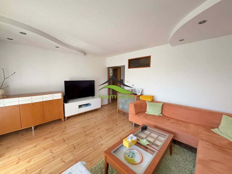 Living room in a 4-room apartment with a wooden decor floor and an orange sofa.