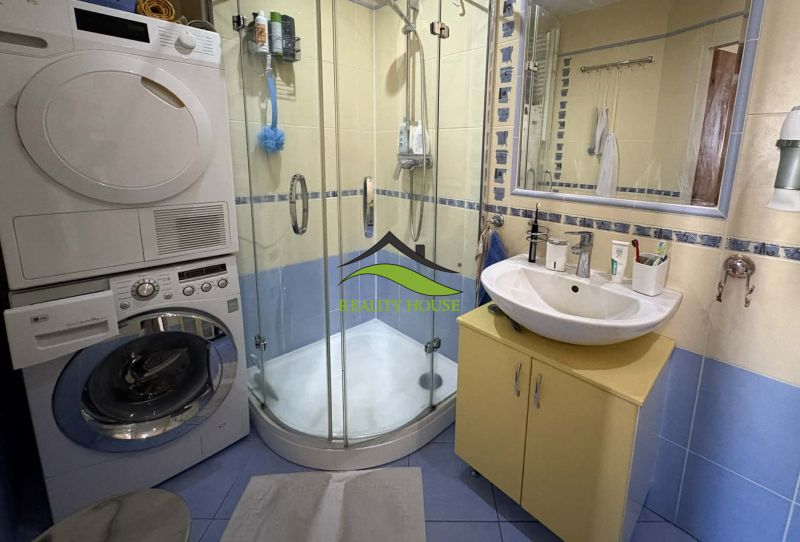 Bathroom with a shower, sink, washing machine, and dryer in a 4-room apartment.