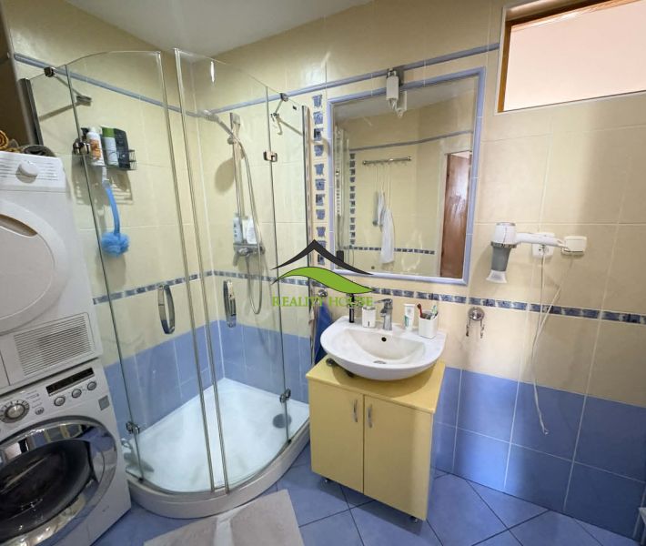 A bathroom with a shower and a washing machine in a 4-room apartment.