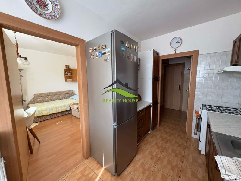 A kitchen with a refrigerator, stove, and wood-patterned flooring in a 4-room apartment.