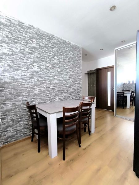 Dining room in a 3-room apartment with stone cladding and a wooden decor floor.