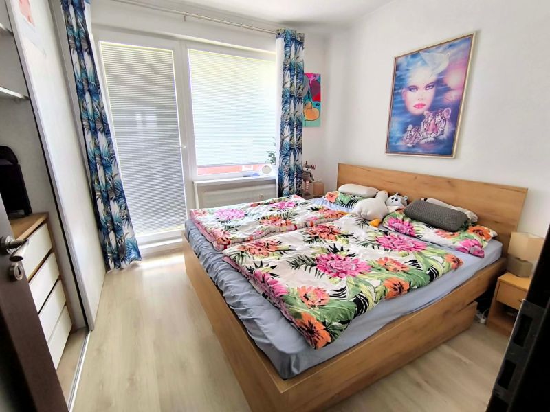A bedroom in a 3-room apartment with a wooden decor floor and colorful bedding.
